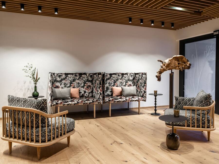 A modern living room with a wooden floor, two patterned sofas, a wooden coffee table, and a decorative skull.