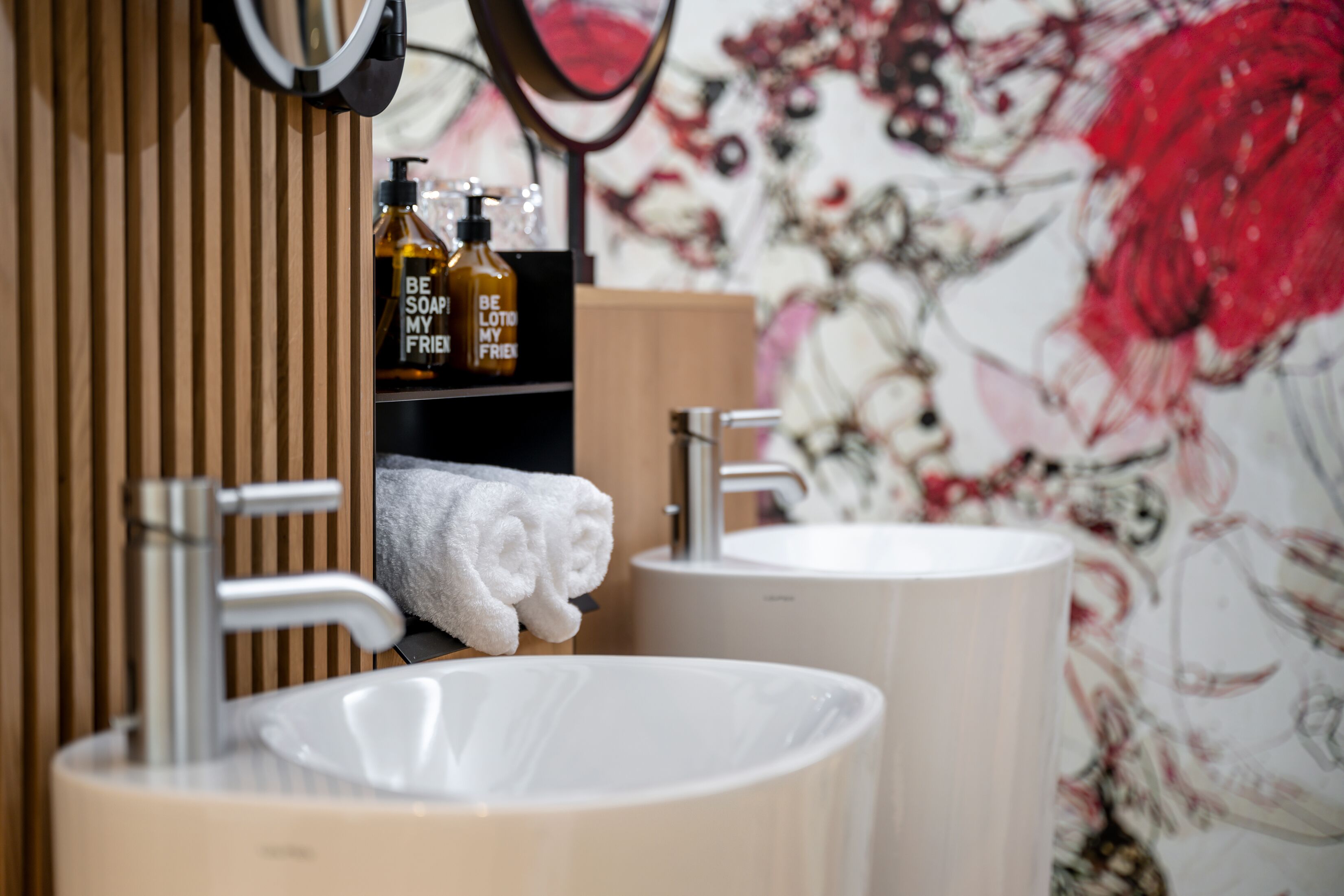 A bathroom with two sinks, a mirror, and a towel rack.