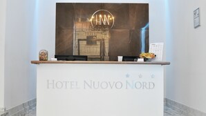 En hotellreception med modern design, utrustad med en stor, upplyst skylt ovanför och hotellets namn tydligt synligt.