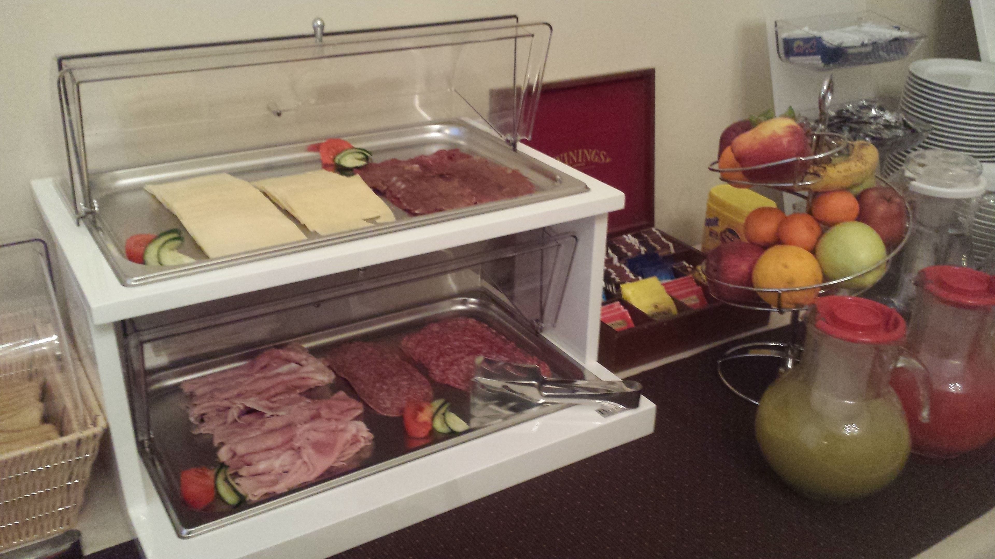 Un buffet proposant une variété de plats, notamment des viandes, des fromages et des fruits.