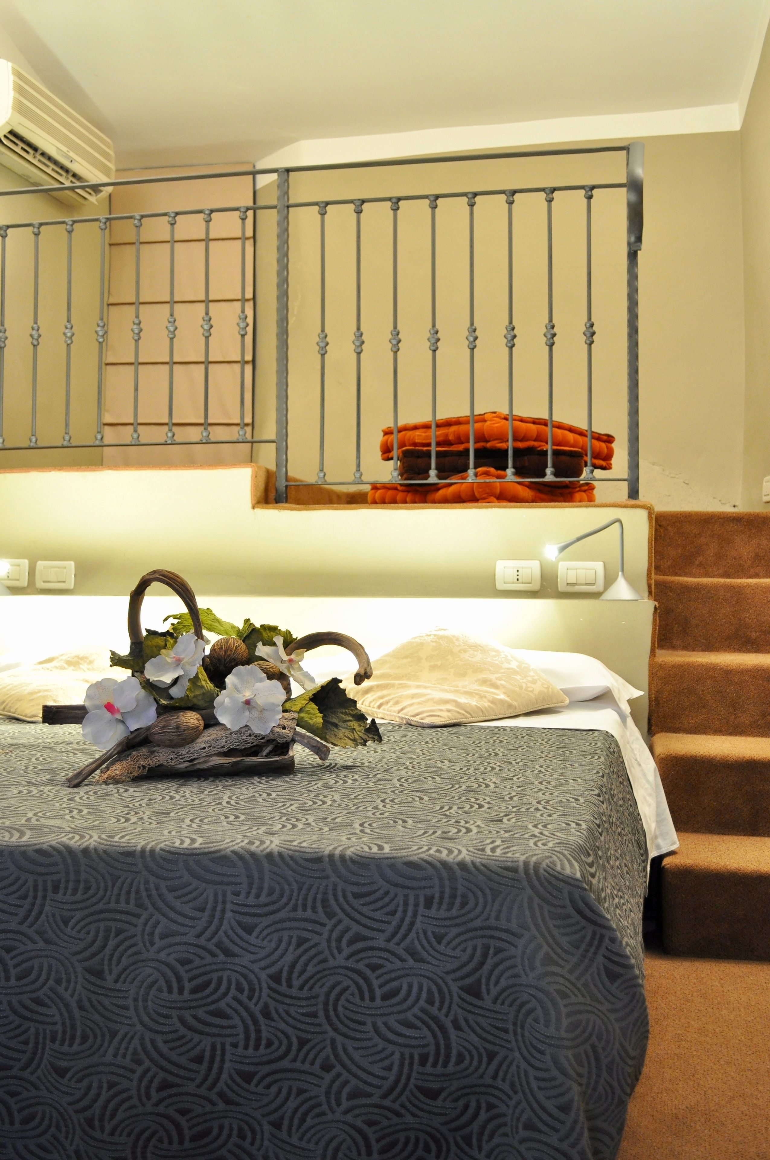 Una habitación de hotel con una cama, una mesita de noche, una lámpara y una escalera.