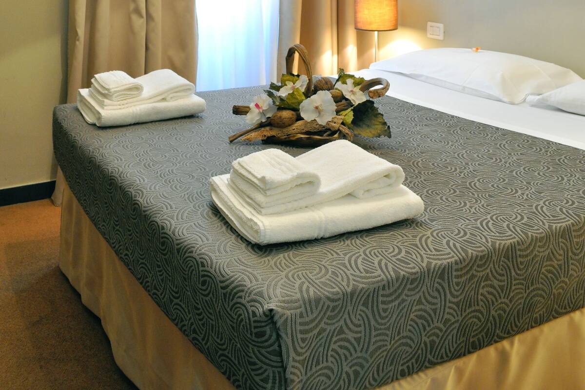 Een hotelkamer met een bed, een lamp en een raam met gordijnen.