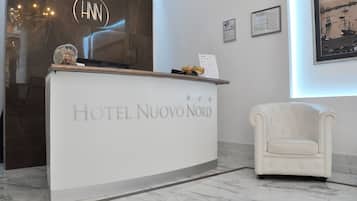Ein Hotelrezeptionstresen mit dem Schriftzug "HOTEL NUOVO NORD" und einem gerahmten Bild an der Wand.