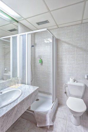A modern bathroom with a glass-enclosed shower, a marble sink, and a toilet. - Carl Inn (Prague)
