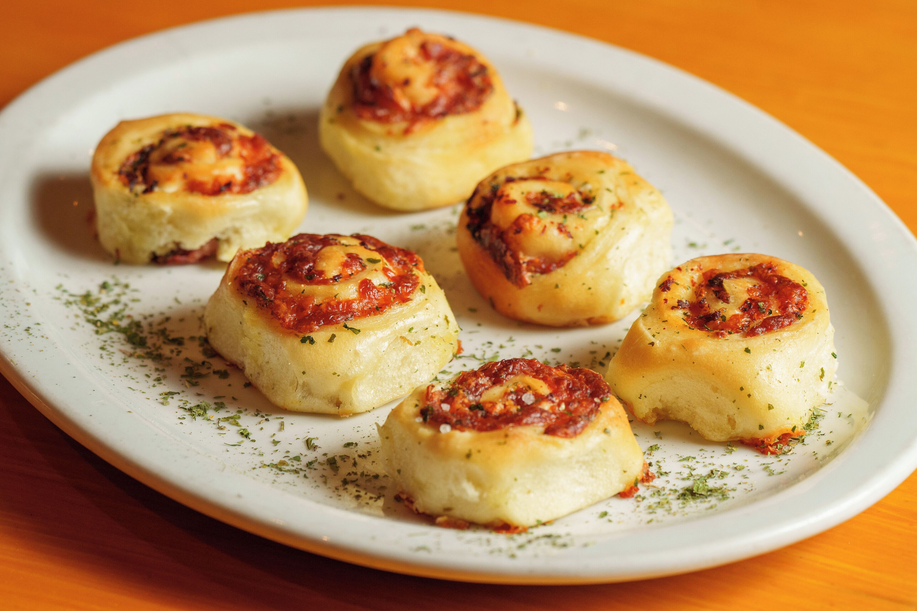 Un plato de rollos de queso adornados con hierbas.