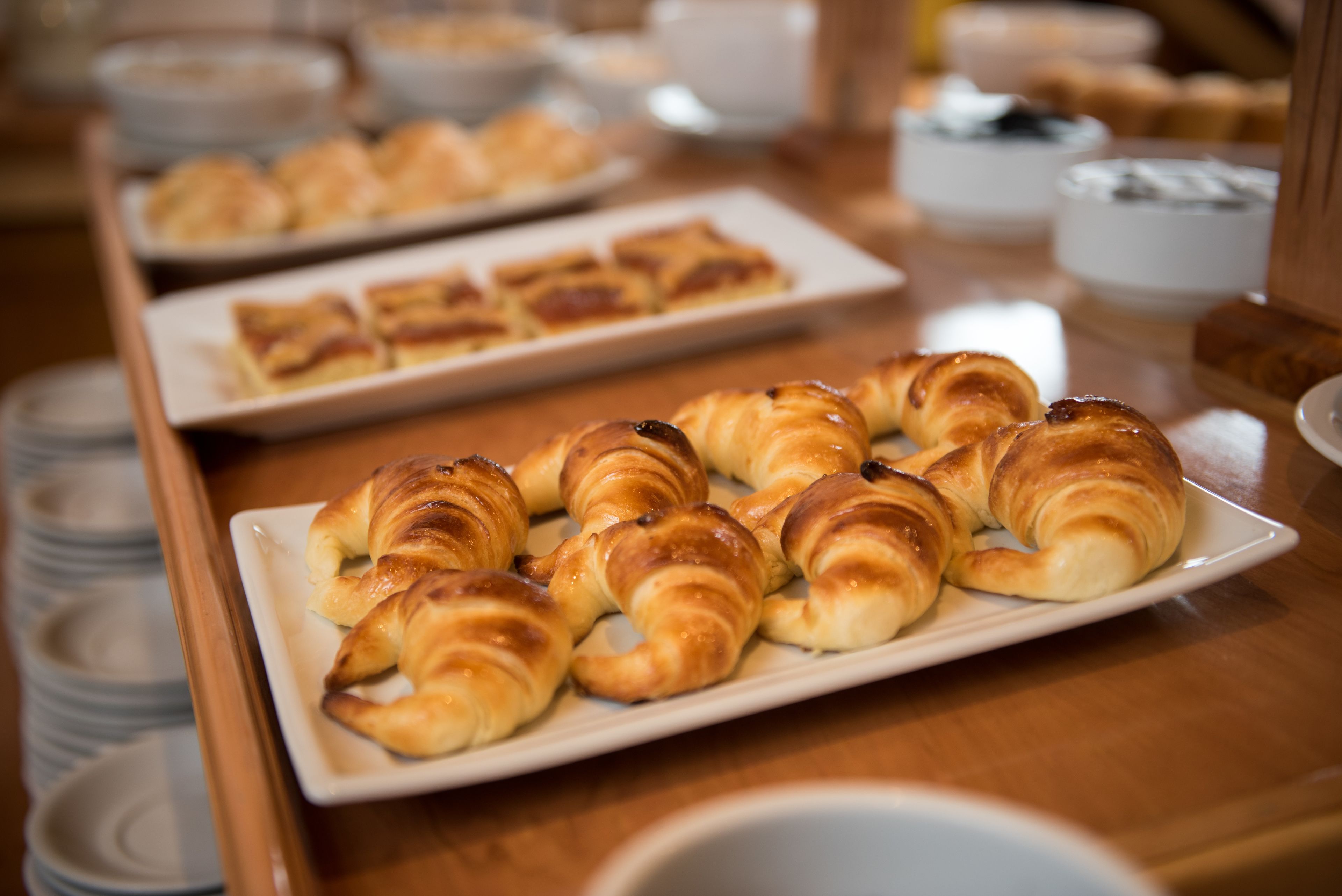 A buffet table with various baked goods, including croissants and pastries.