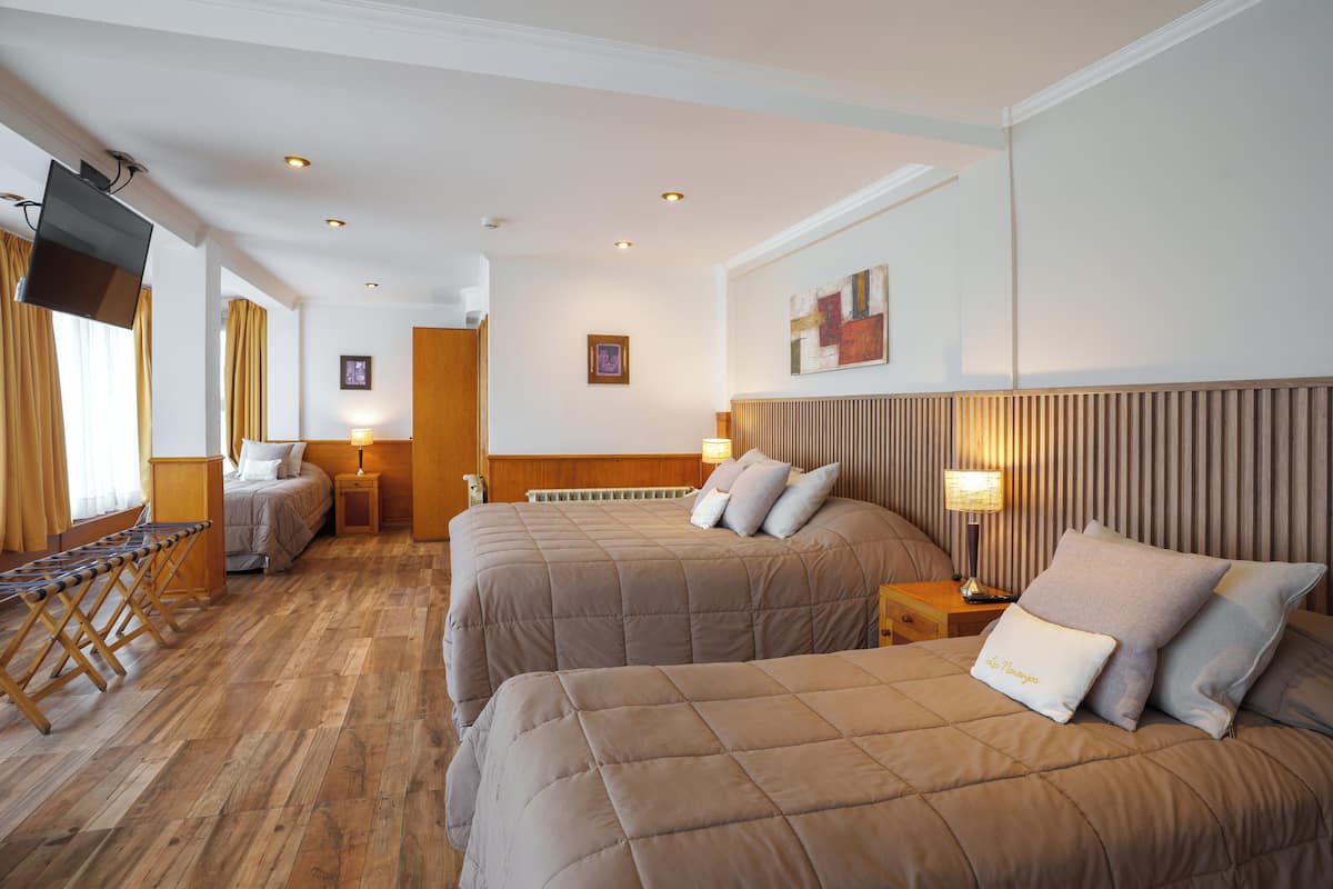 A hotel room with two beds, a TV, a wooden floor, and a view of the city.