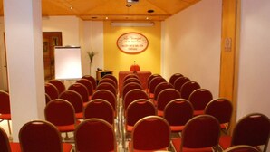 A conference room with rows of red chairs, a podium, and a whiteboard. - Los Naranjos (Ushuaia)
