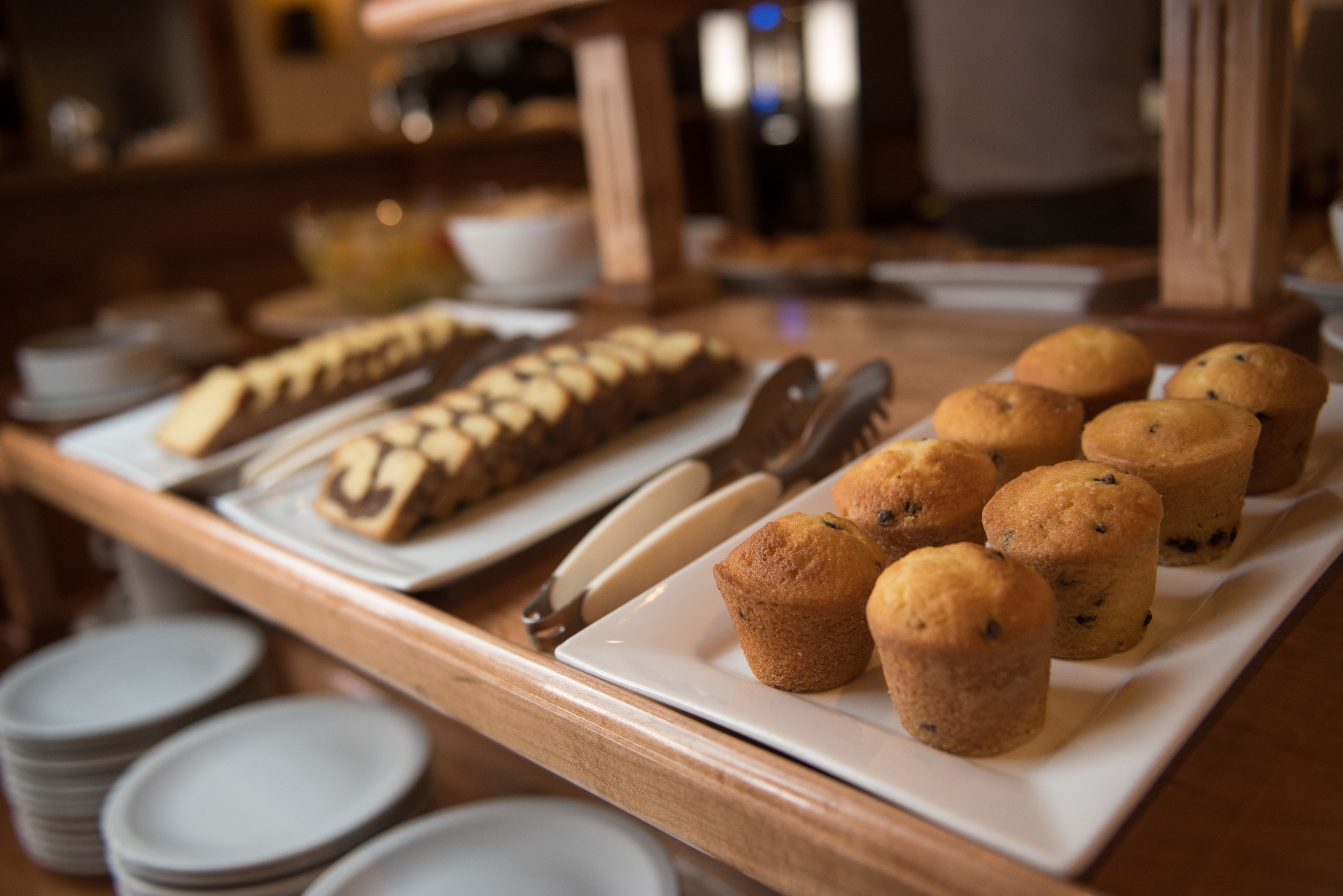 Una mesa de bufé con diversas opciones de panadería, como muffins y pasteles, y un cuchillo sobre un plato blanco.