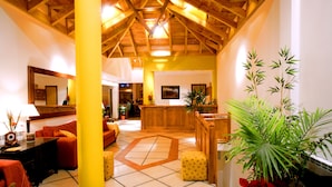 A spacious lobby with a high ceiling, a reception desk, and a large potted plant. - Los Naranjos (Ushuaia)