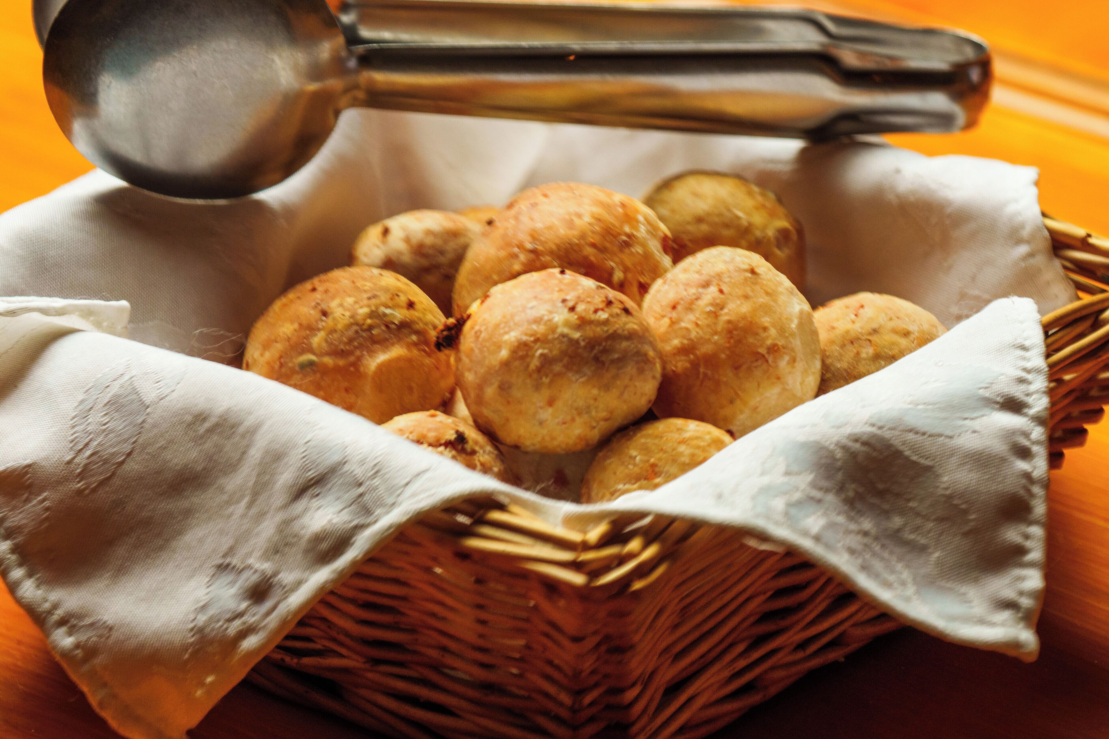 Un panier rempli de petits pains ronds, dorés et croustillants, posé sur une table en bois.