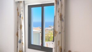 Une pièce avec une fenêtre, des rideaux et une vue sur la mer.