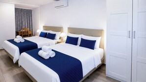 Une chambre d’hôtel avec deux lits, une armoire et un coin repas comprenant une chaise et une table.