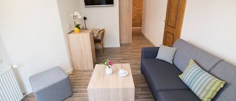 Una sala de estar moderna con un sofá gris, una mesa de centro de madera y un televisor montado en la pared.