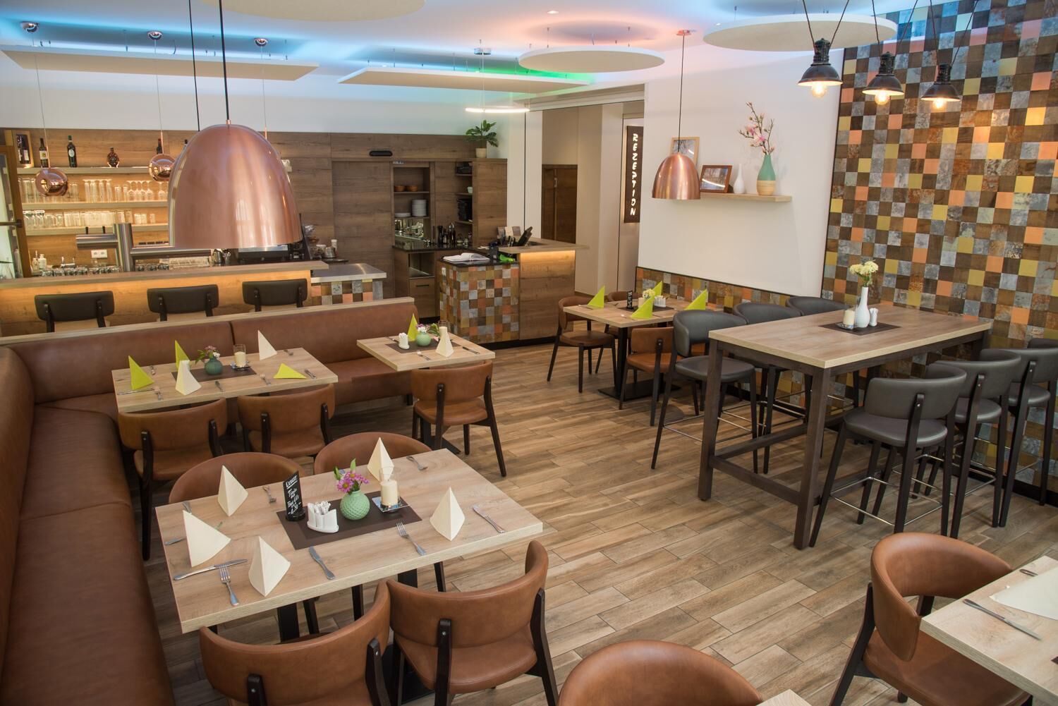 Un restaurante con mesas de madera, asientos de cuero marrón y una barra, además de un mostrador de recepción.