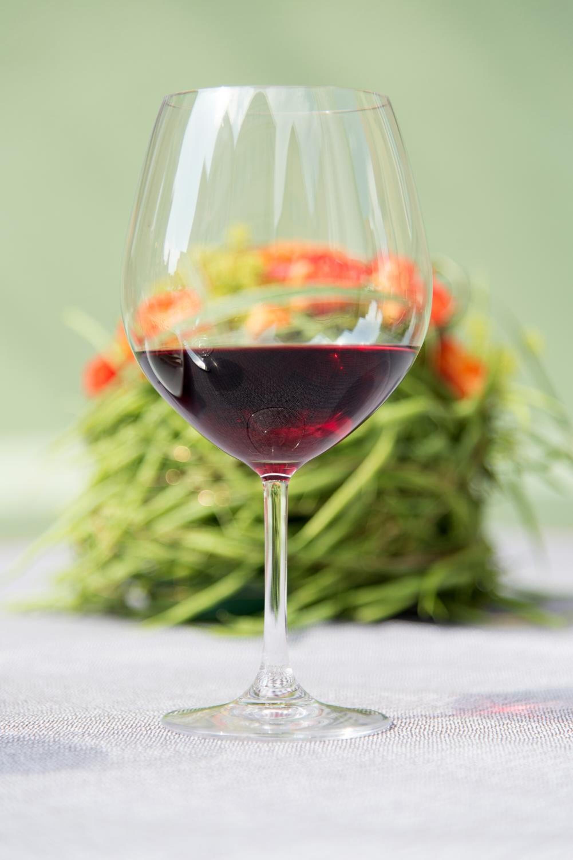 A wine glass with red wine on a table.