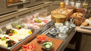 Un bufé con diversas opciones de comida, incluyendo carnes, quesos y frutas frescas.