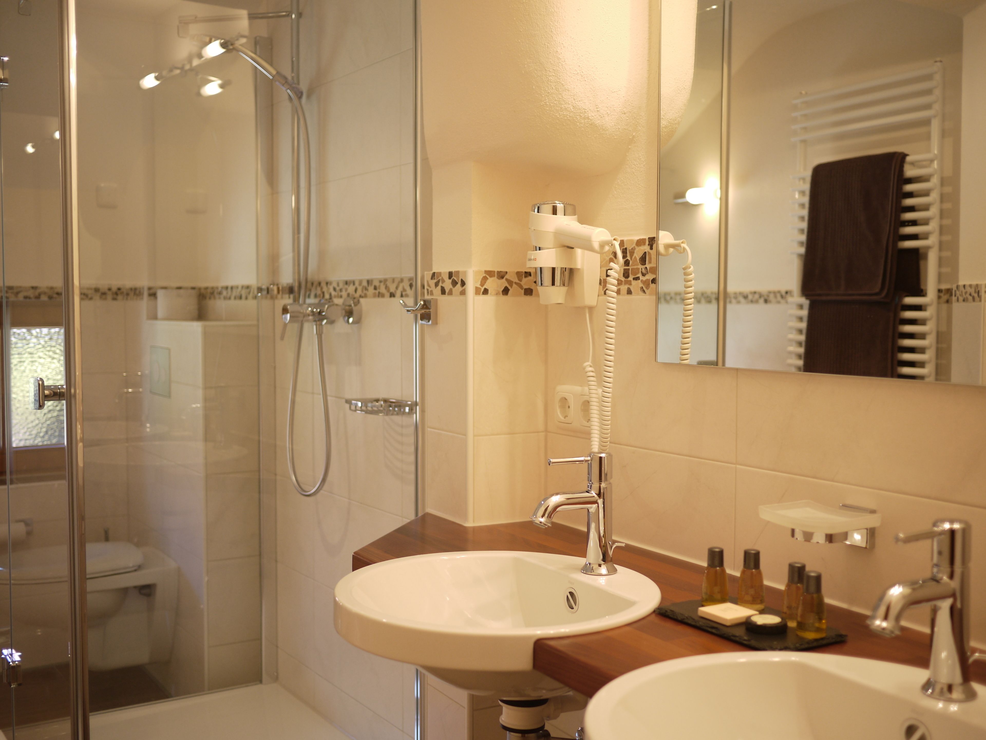 Un baño moderno con ducha acristalada, lavabo blanco y espejo sobre él.