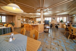 Une cuisine spacieuse dotée de meubles en bois, d’un îlot central et d’un coin repas avec des nappes à carreaux.