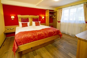 Une chambre d’hôtel avec un lit en bois, des murs rouges et un plancher en bois.