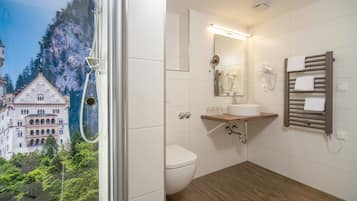 Un bagno con pavimento in legno, un WC bianco, un lavabo con specchio sopra e un porta asciugamani.