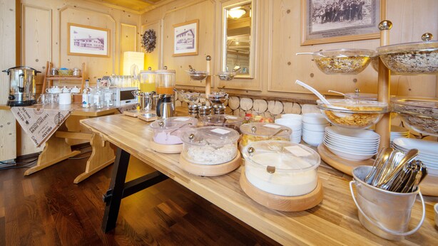 Ein reichhaltiges Buffet mit verschiedenen Speisebehältern, Servierbesteck und einem Holztisch.