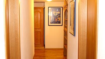A narrow hallway with wooden doors and a framed picture on the wall.