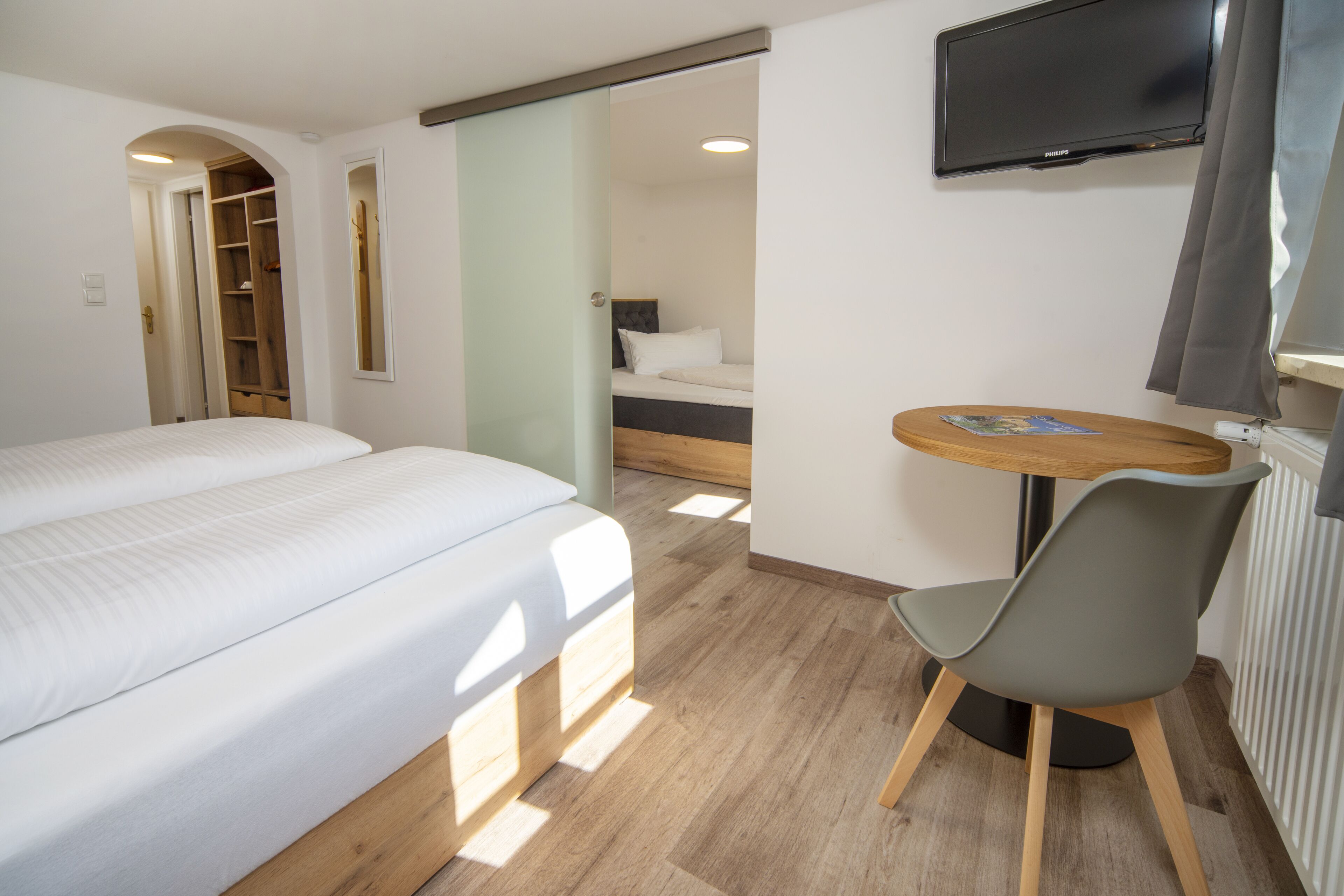 Une chambre d’hôtel comprenant un lit, un bureau avec une chaise, une télévision et une armoire.