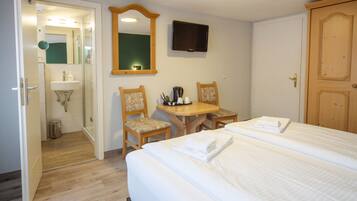 A hotel room with a bed, a desk, two chairs, a mirror, a television, and a wardrobe.