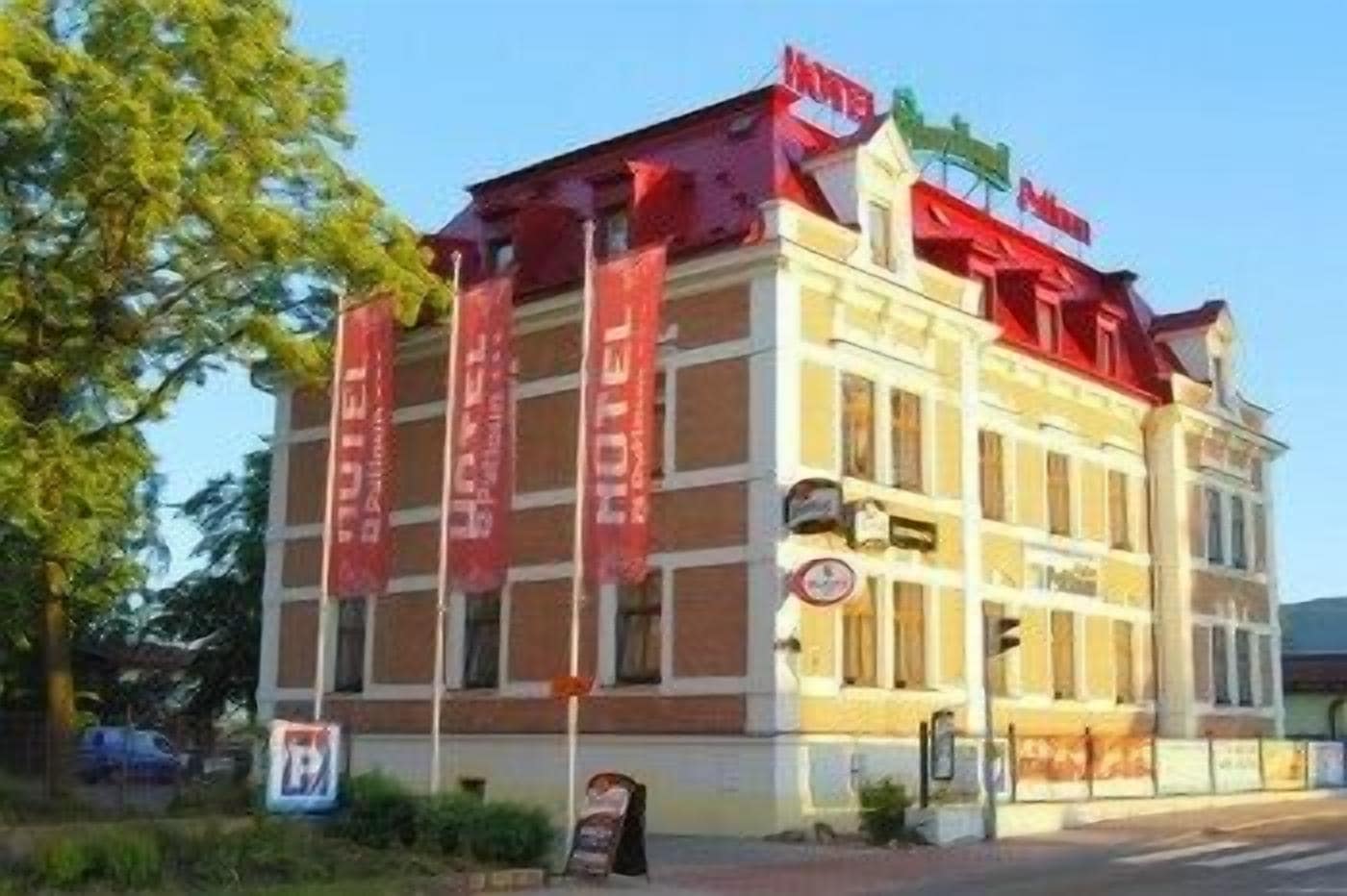 Un hôtel à plusieurs étages, avec une enseigne rouge et une entrée bien visible.