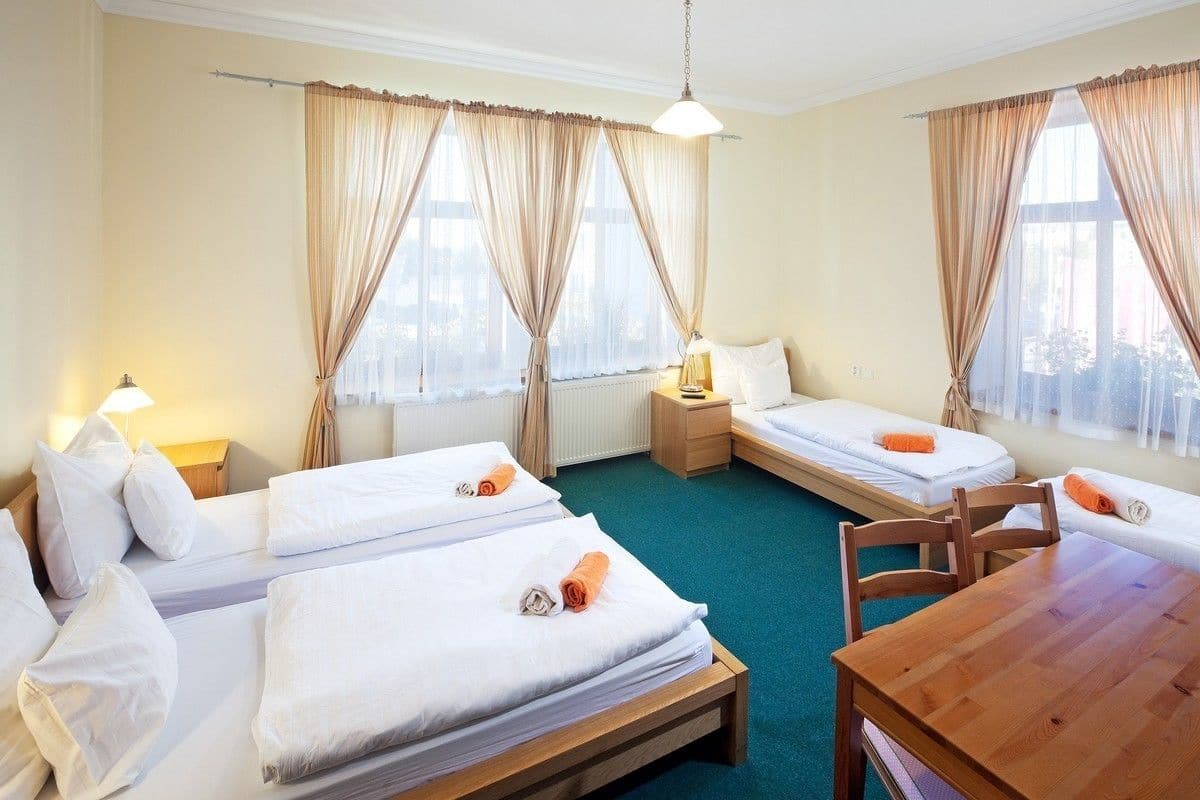 Habitación de hotel con dos camas individuales, una mesa de madera y vistas al exterior a través de amplias ventanas.