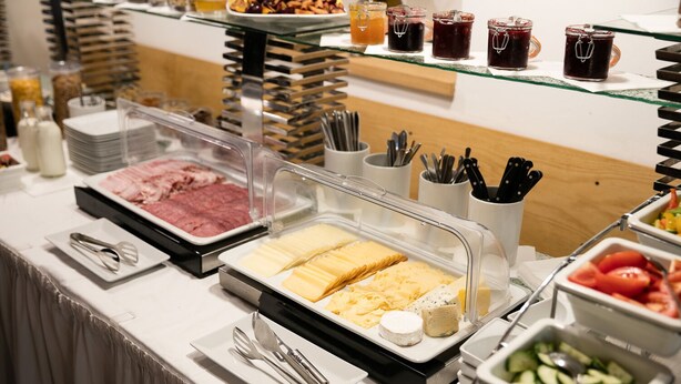 Buffet com diversas opções de comida, incluindo carnes, queijos e frutas.
