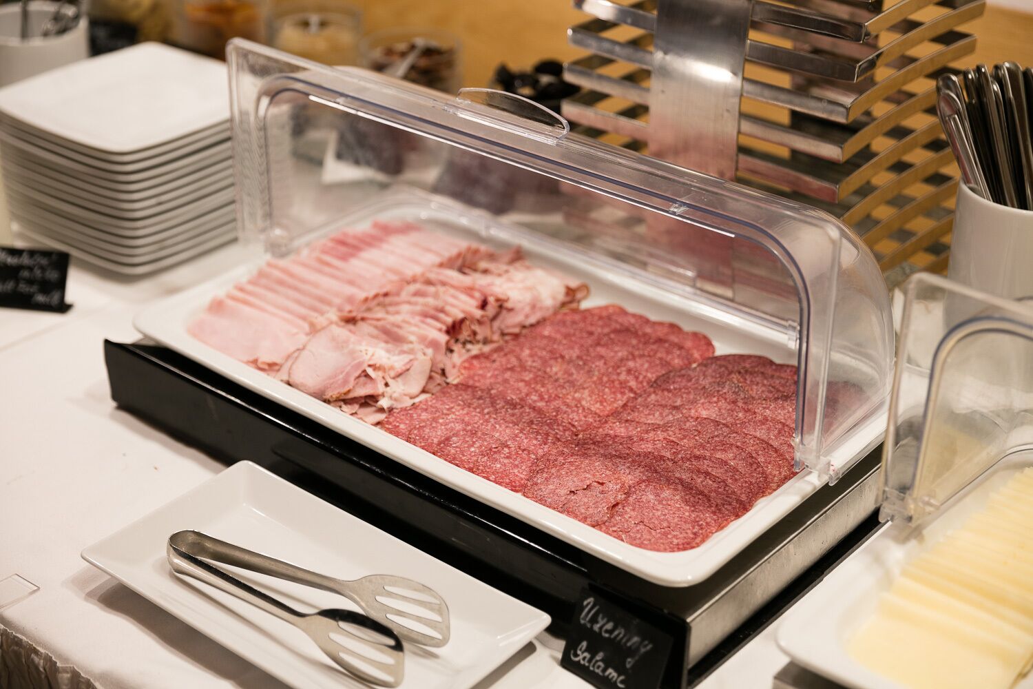 A buffet with various meat options, including sliced ham and salami, and a sign indicating 'Salami'.