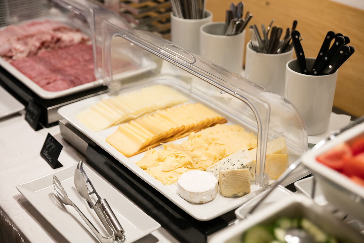 A buffet with various cheeses and meats.