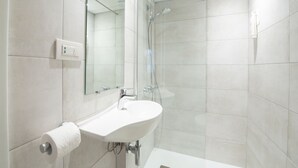 A modern bathroom with a white sink, mirror, and shower. - The Originals Access, Hôtel Bordeaux Aéroport (Merignac)