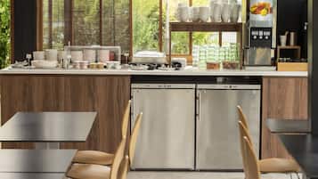 A modern kitchen with a central island, stainless steel appliances, and a dining area with chairs and tables.