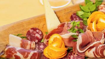 A wooden board with various meats, cheese, and herbs.