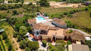 Una amplia villa con piscina, rodeada de exuberante vegetación y vistas al mar.