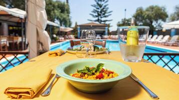 A dining table with a bowl of food, a glass of water, and a bottle of lemon.