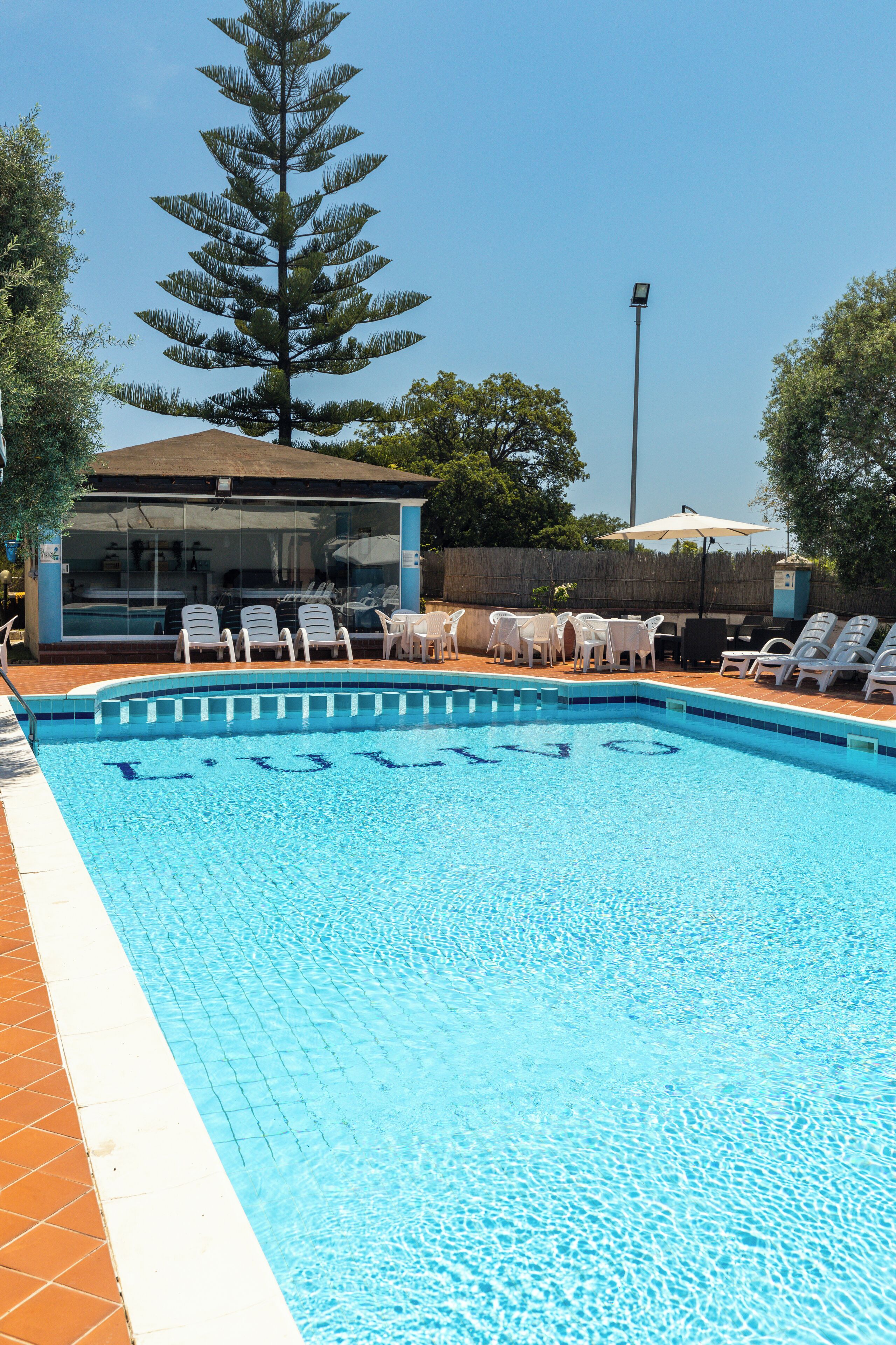 A swimming pool with lounge chairs and a glass-enclosed building.