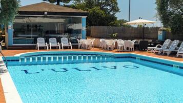 A swimming pool with lounge chairs and a glass-enclosed building.