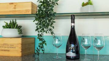 A bottle of wine, two glasses, a wooden crate, and a potted plant on a kitchen counter.
