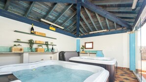 Un cuarto de spa con dos tinas de hidromasaje, vigas de madera en el techo y suelo de baldosas.