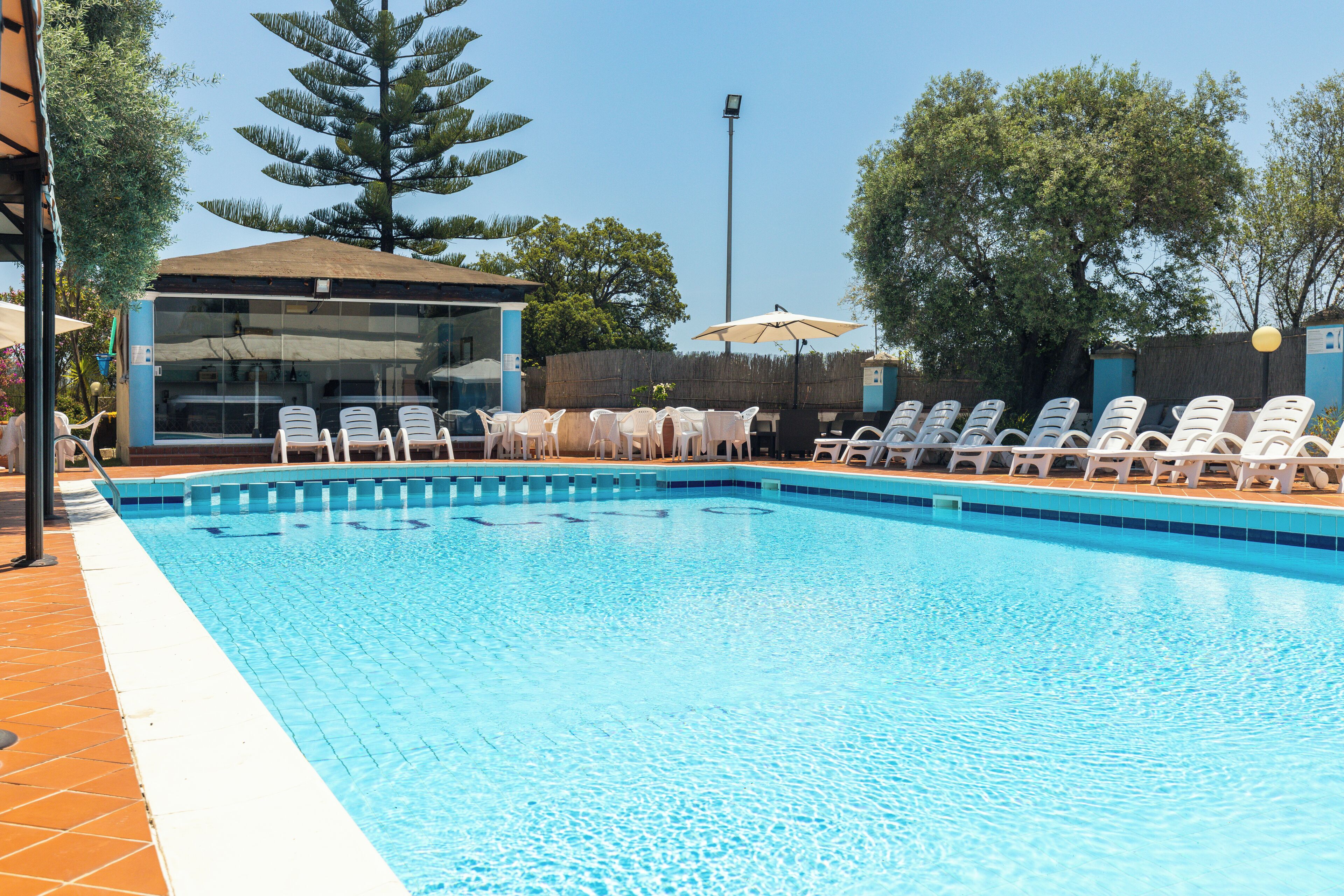 Una piscina con sillas de descanso y un edificio con ventanas amplias.