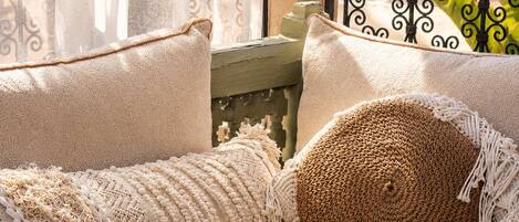A cozy outdoor seating area with a woven pouf, a woven hat, and a terracotta pot.