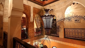 A courtyard with arches, a hanging lantern, and a palm tree. - Riad Jona (Marrakech)