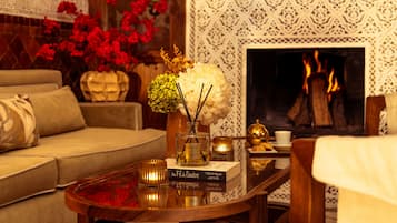 A cozy living room with a sofa, a coffee table with decorative items, a fireplace, and a patterned wall.