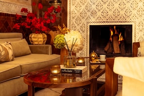Una sala de estar acogedora con un sofá, una mesa de centro con adornos, una chimenea y un papel tapiz con diseño.