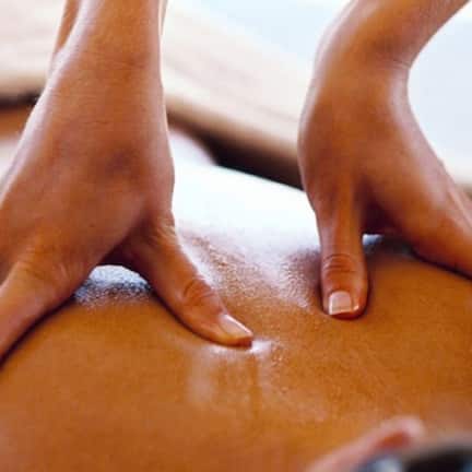 A close-up of hands performing a massage on a person's back.
