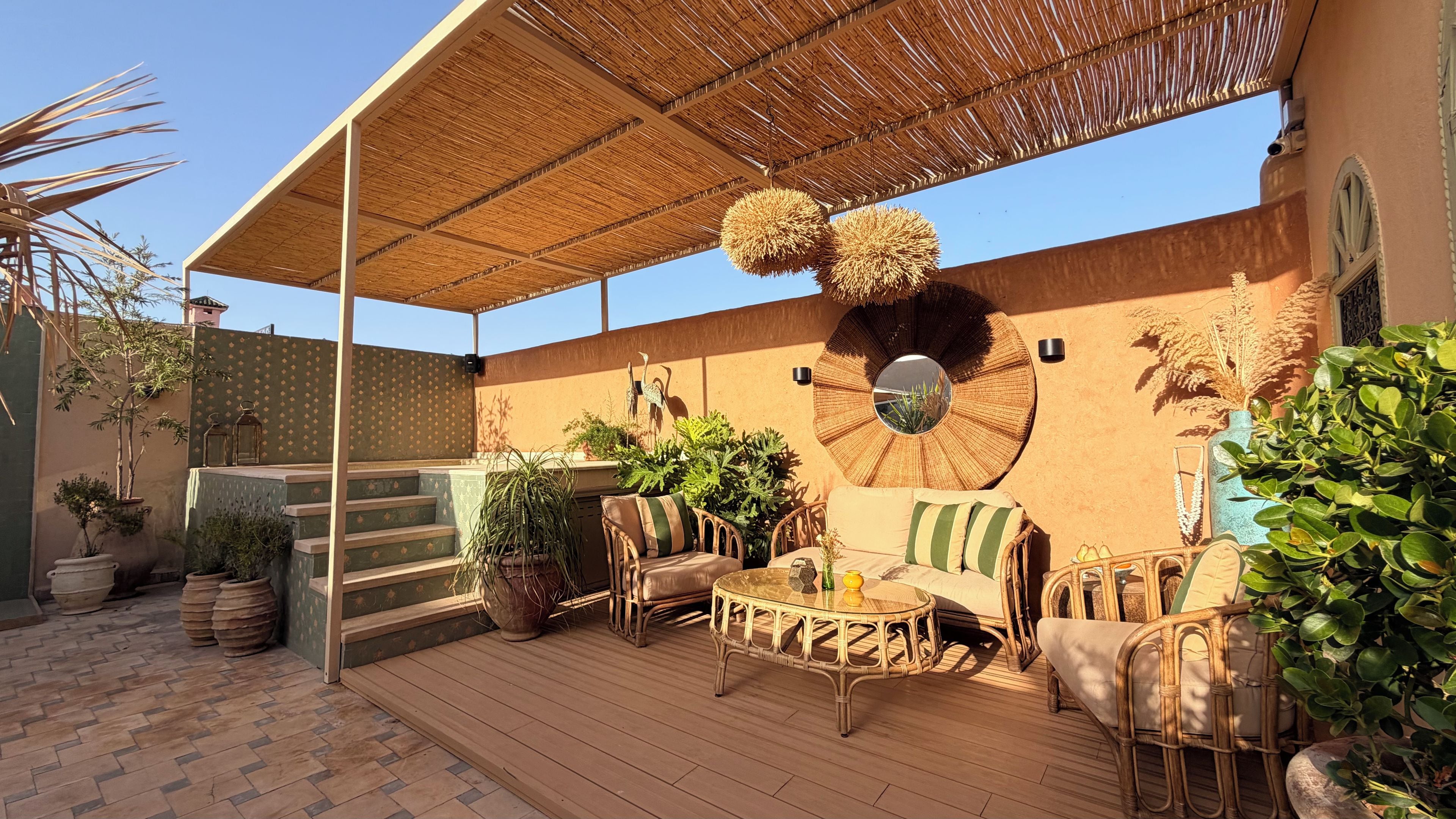 An outdoor patio with wicker furniture, a round mirror, and potted plants.